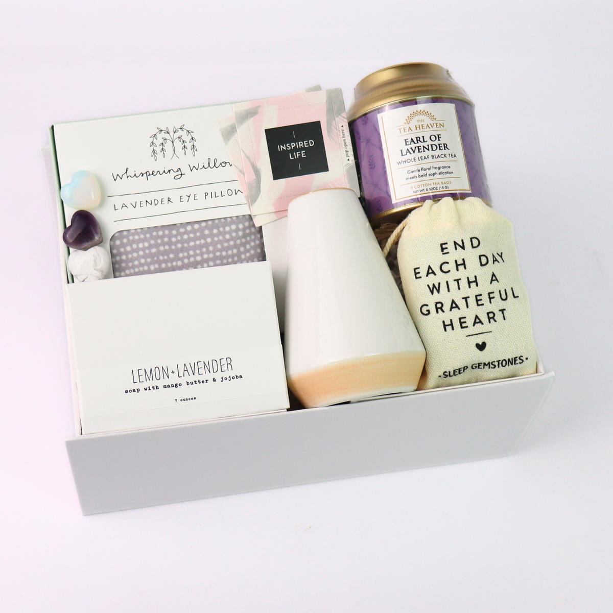 Gift set with lavender eye pillow, tea, and candle on a white background