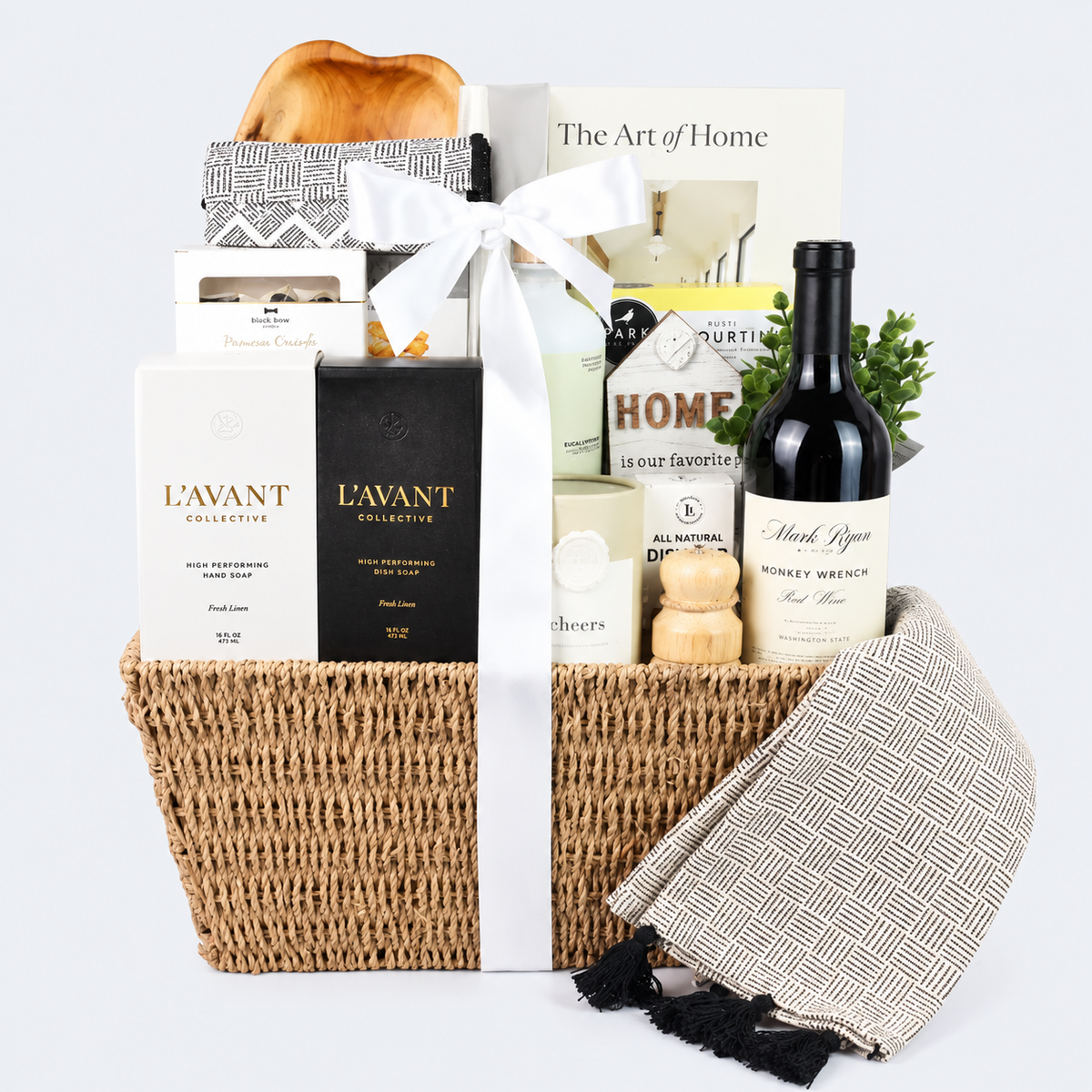 Luxury housewarming gift basket with wine, washington made hand soap, lotion, cutting board, crackers, almonds, and a beautiful book, displayed in a woven basket with a sage satin bow.